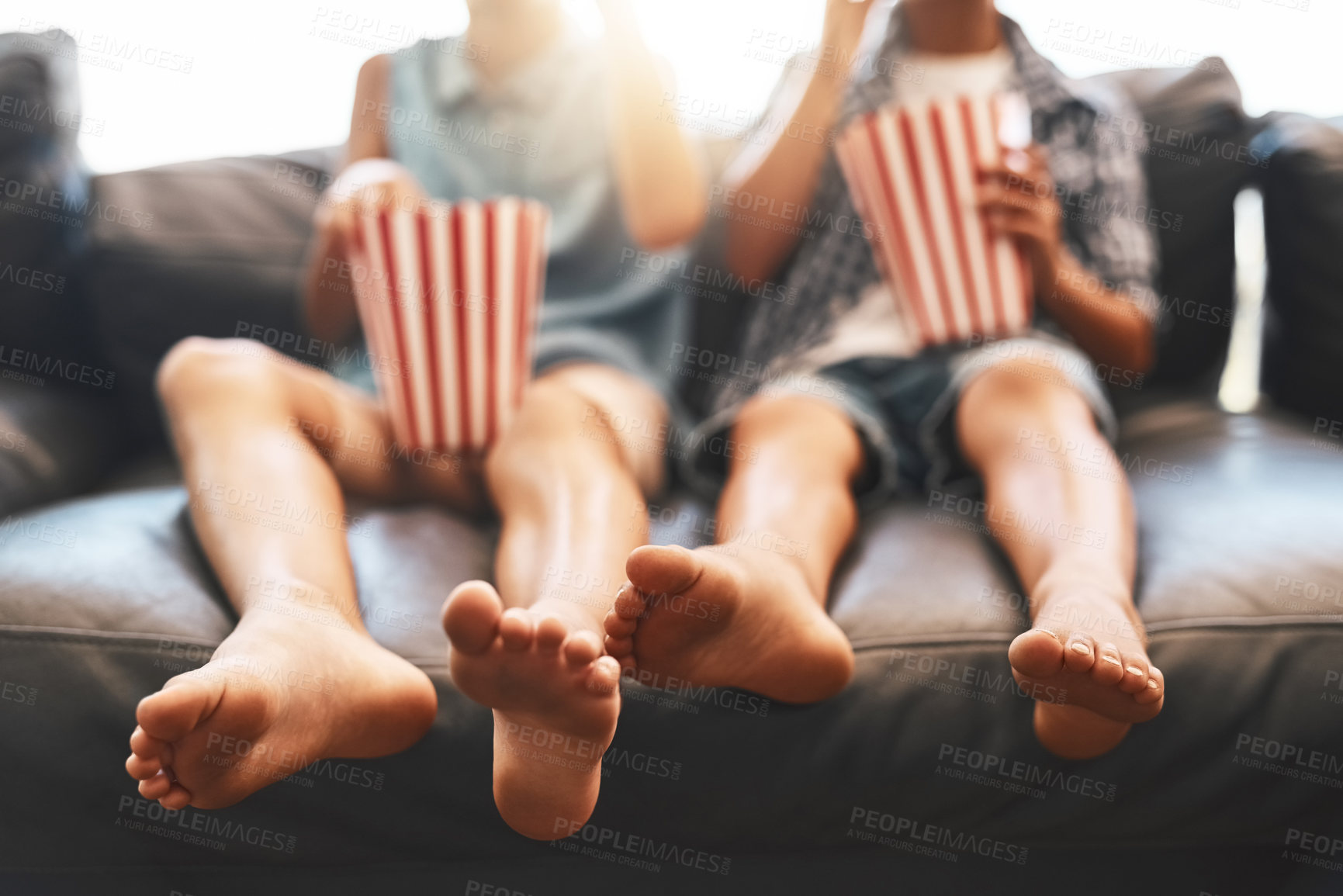 Buy stock photo Cropped shot of a brother and sister eating popcorn and watching movies on the sofa at home