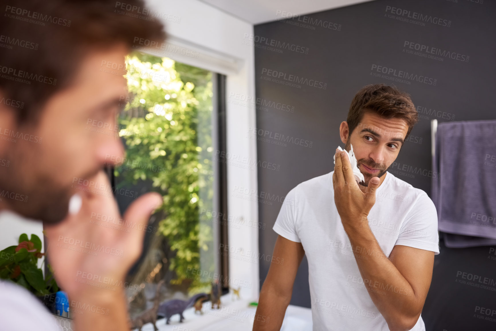 Buy stock photo Cropped shot of a handsome man applying shaving cream on to his face in the bathroom at home