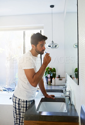 Buy stock photo Cropped shot of a handsome man brushing his teeth in the bathroom at home
