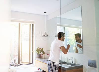 Buy stock photo Cropped shot of a handsome man looking in the mirror and  rinsing his mouth in the bathroom at home