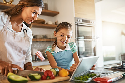 Buy stock photo Shot of a mother and her young daughter trying out a new recipe in the kitchen together