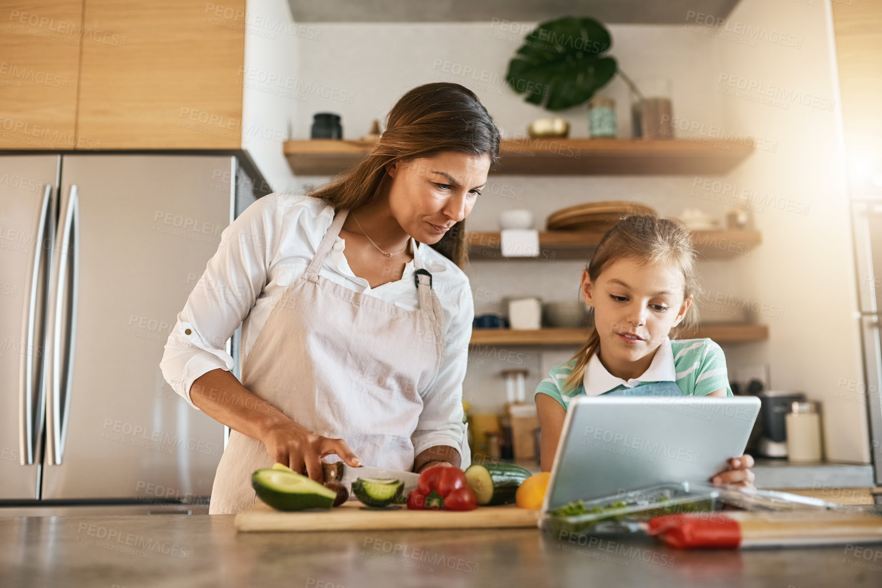 Buy stock photo Woman, child and cooking with tablet, online for recipe or ingredients on kitchen counter for dinner. Family, healthy and food or meal prep for nutrition, together or bonding for clean eating in home