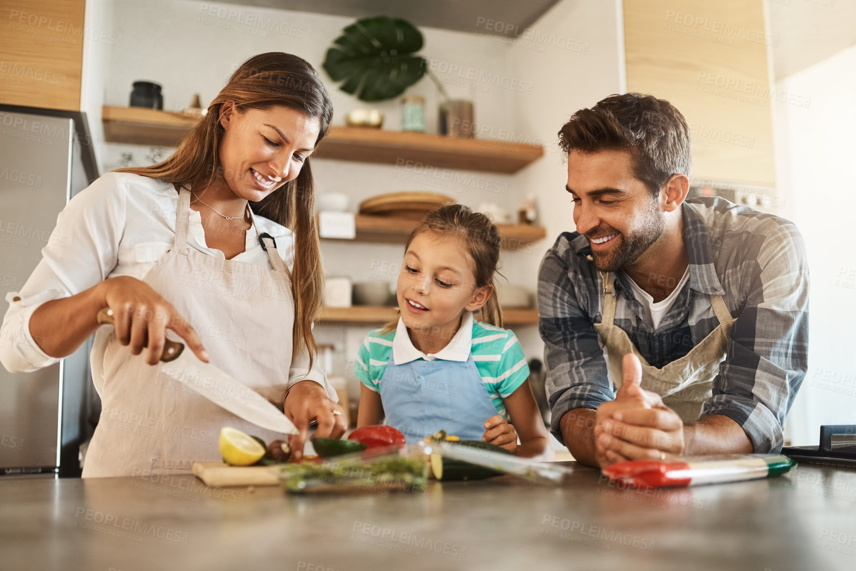 Buy stock photo Shot of a happy young family cooking together in their kitchen at home