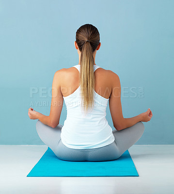 Buy stock photo Studio shot of a healthy young woman meditating against a blue background