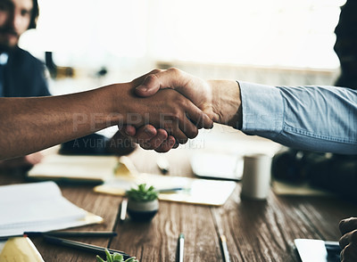 Buy stock photo Shot of two unidentifiable businesspeople shaking hands over the boardroom table during a meeting