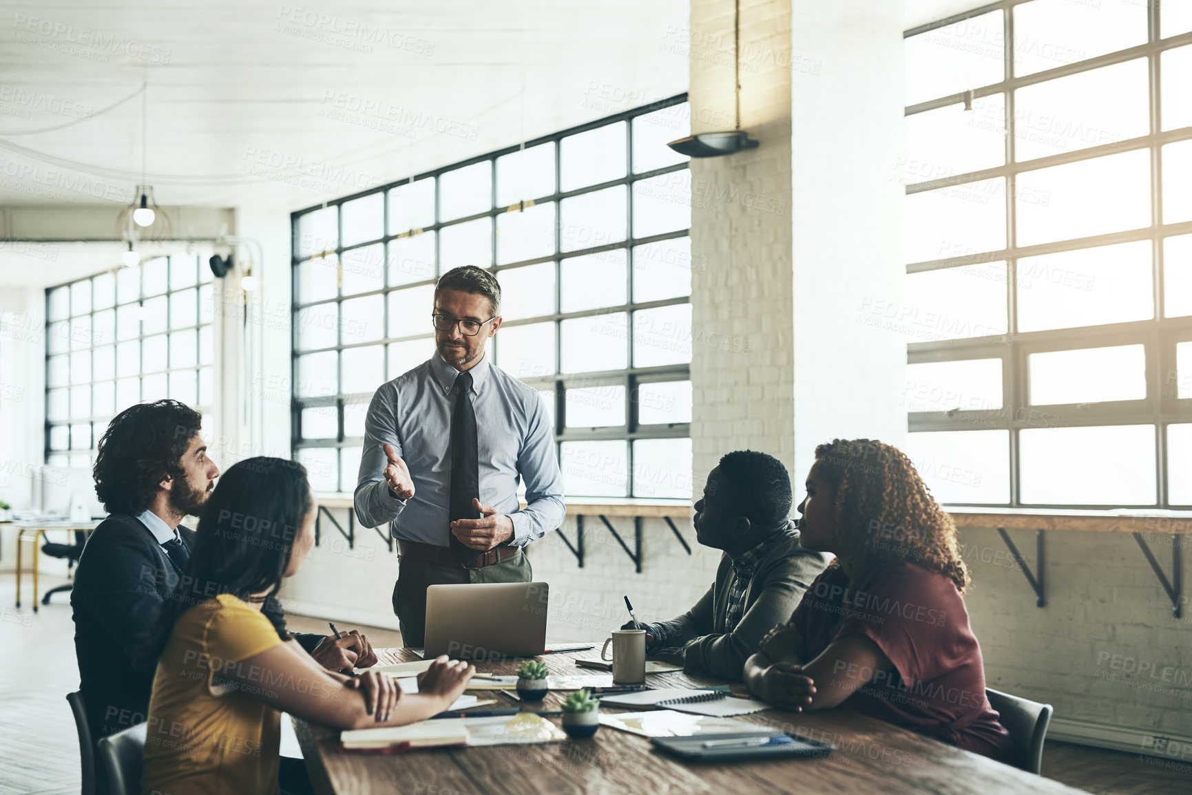 Buy stock photo Shot of a well-dressed businessman presenting a new idea to his colleagues in the office