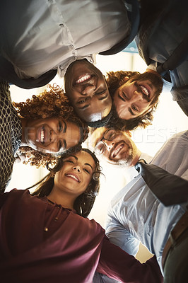 Buy stock photo Low angle portrait of a team of happy businesspeople putting their heads together in a huddle