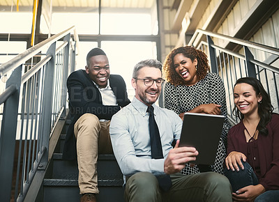 Buy stock photo Shot of a diverse group of colleagues having an impromptu meeting with a tablet on the stairs