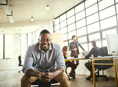Buy stock photo Cropped portrait of a handsome young businessman sitting in the office with his colleagues in the background