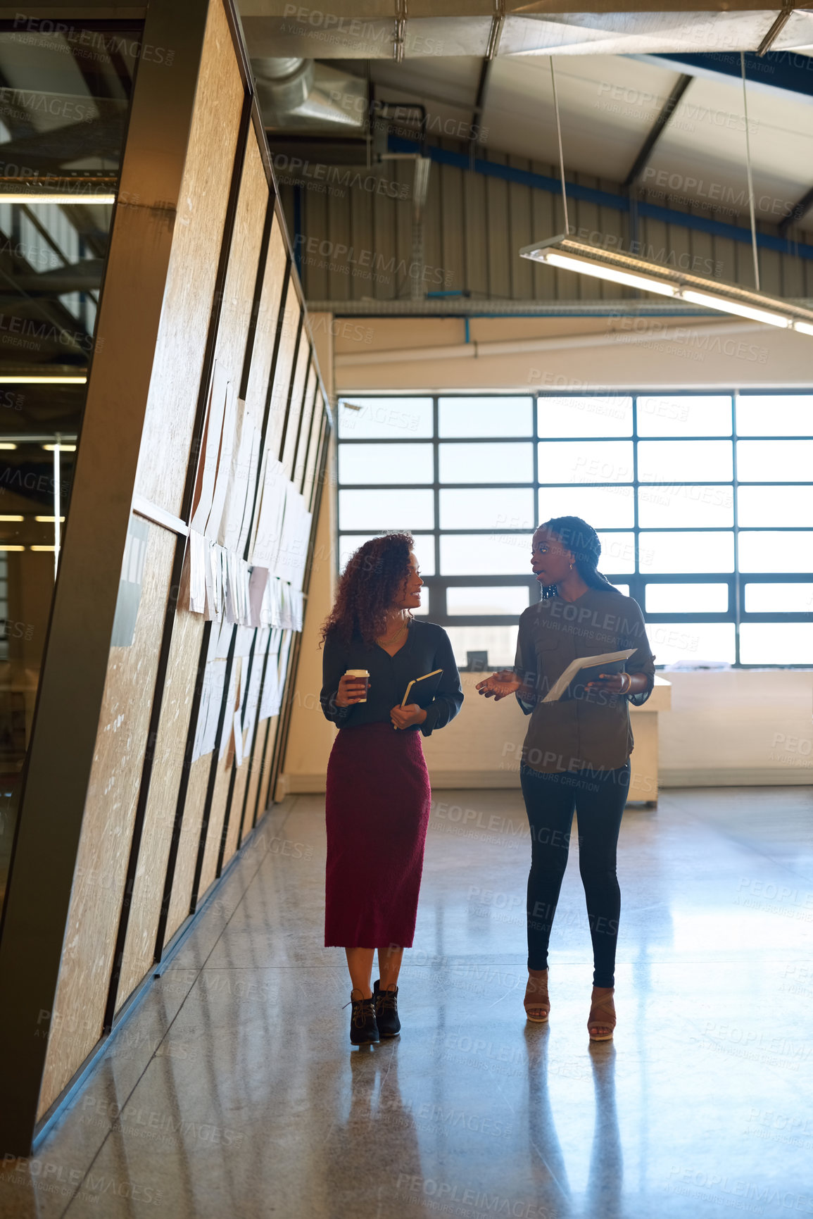 Buy stock photo Shot of two businesswomen having a discussion while walking through a office