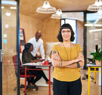 Buy stock photo Shot of a creative businesswoman standing in her office with colleagues blurred in the background