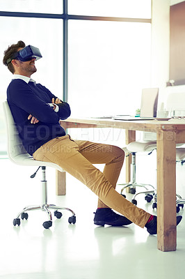 Buy stock photo Shot of a businessman wearing a VR headset while leaning back in his office chair at work