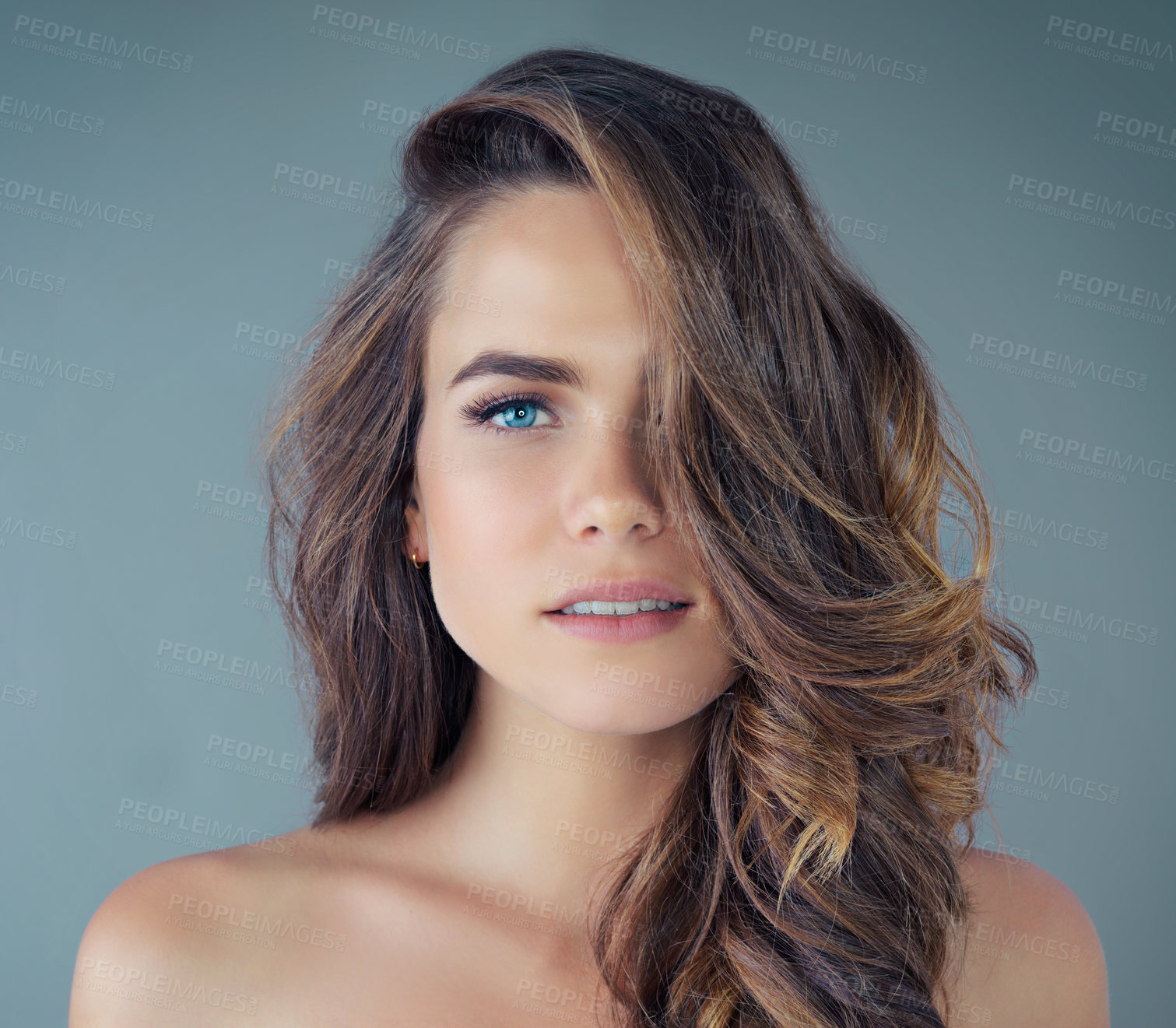 Buy stock photo Cropped portrait of a beautiful young woman posing against a grey background in the studio