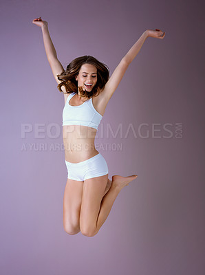 Buy stock photo Studio shot of a healthy young woman arms raised and jumping against a purple background