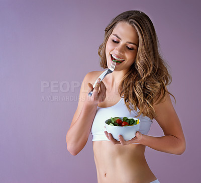 Buy stock photo Studio shot of a healthy young woman eating a salad against a purple background