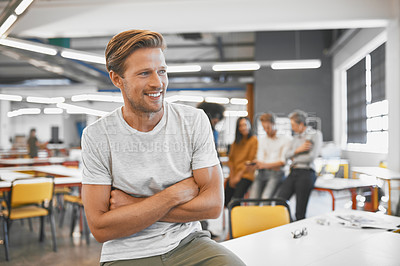 Buy stock photo Cropped shot of a handsome young businessman in the office with his colleagues in the background