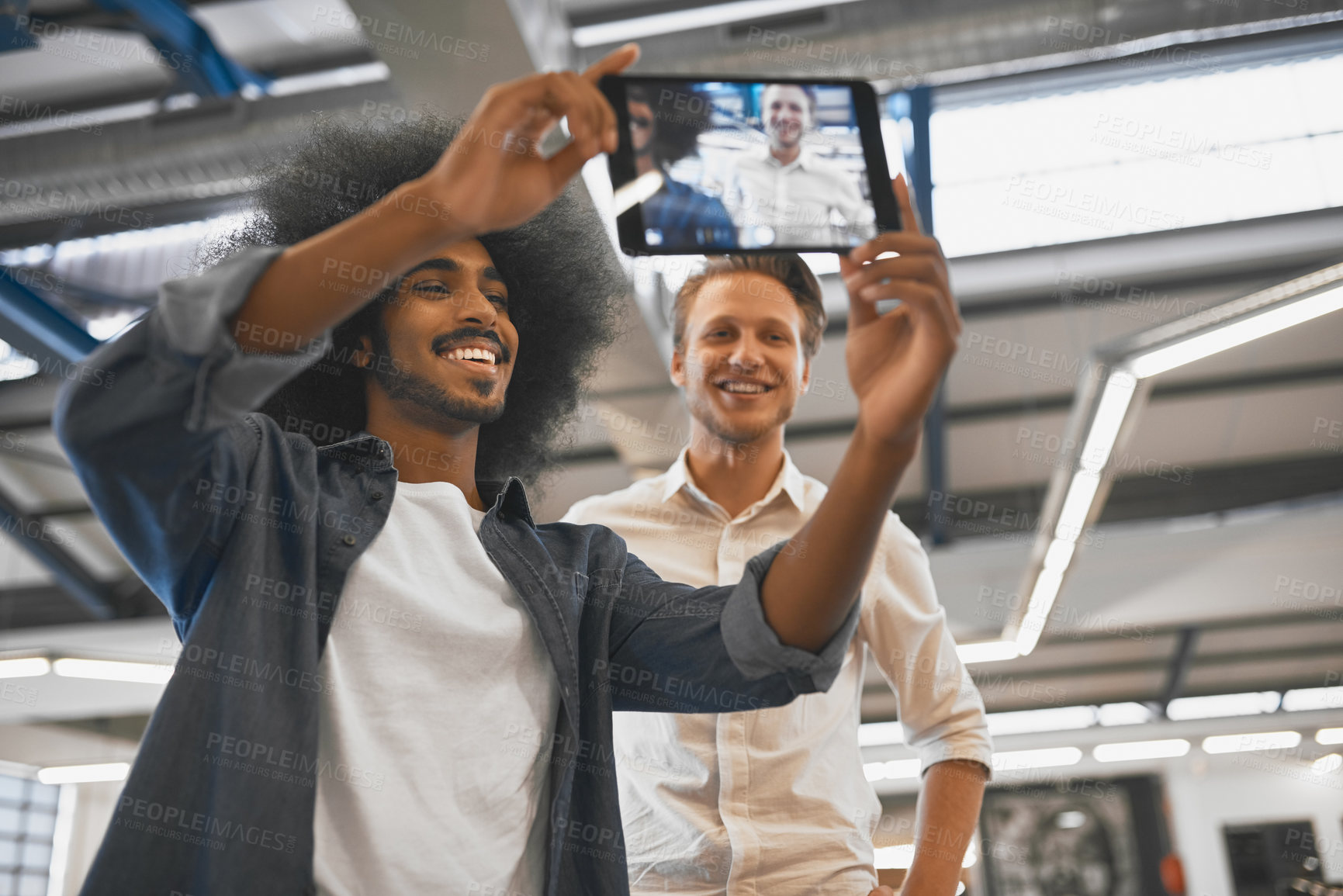 Buy stock photo Cropped shot of two young businessmen taking a selfie with a tablet in their office