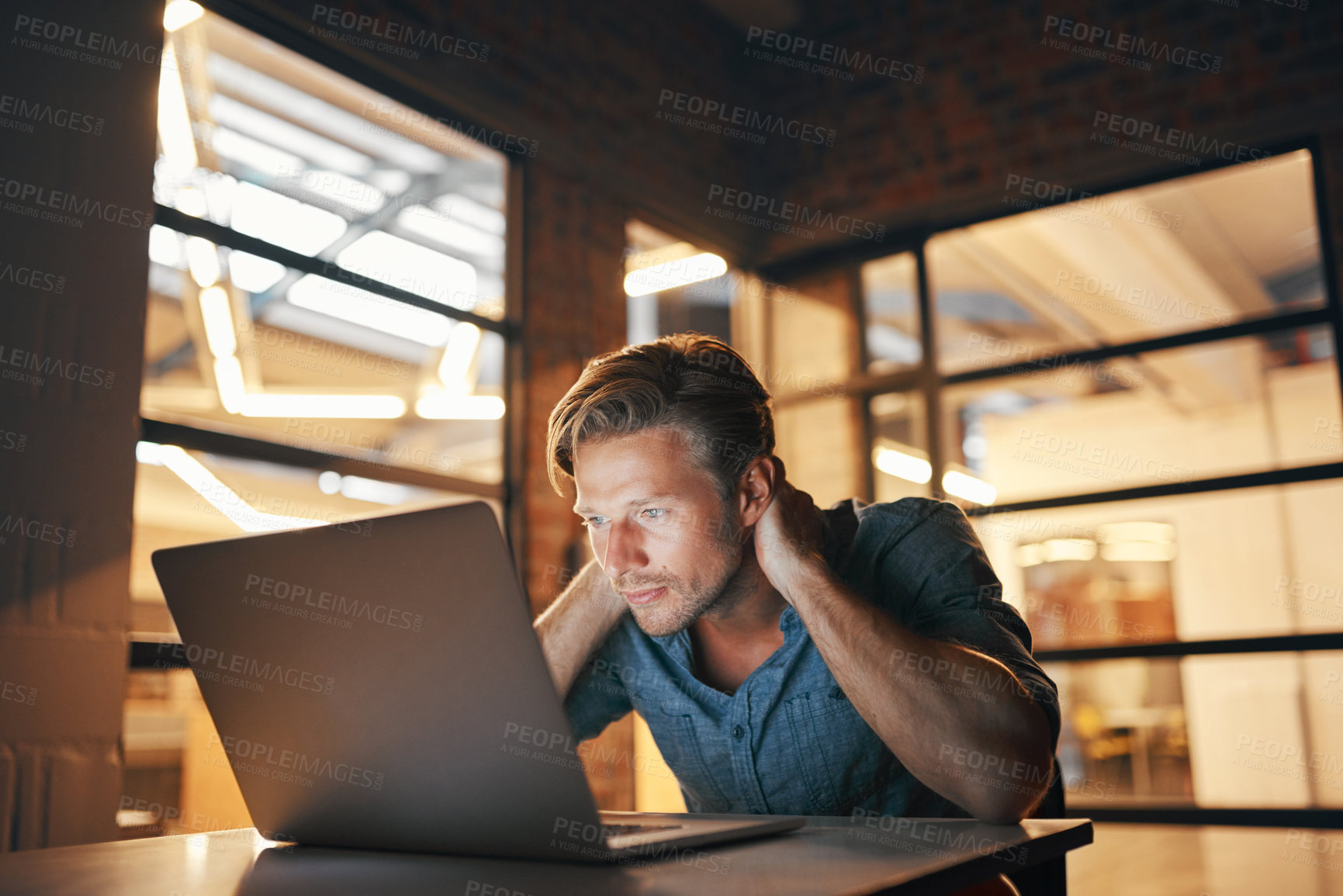 Buy stock photo Shot of a handsome young man looking stressed while working late in his office