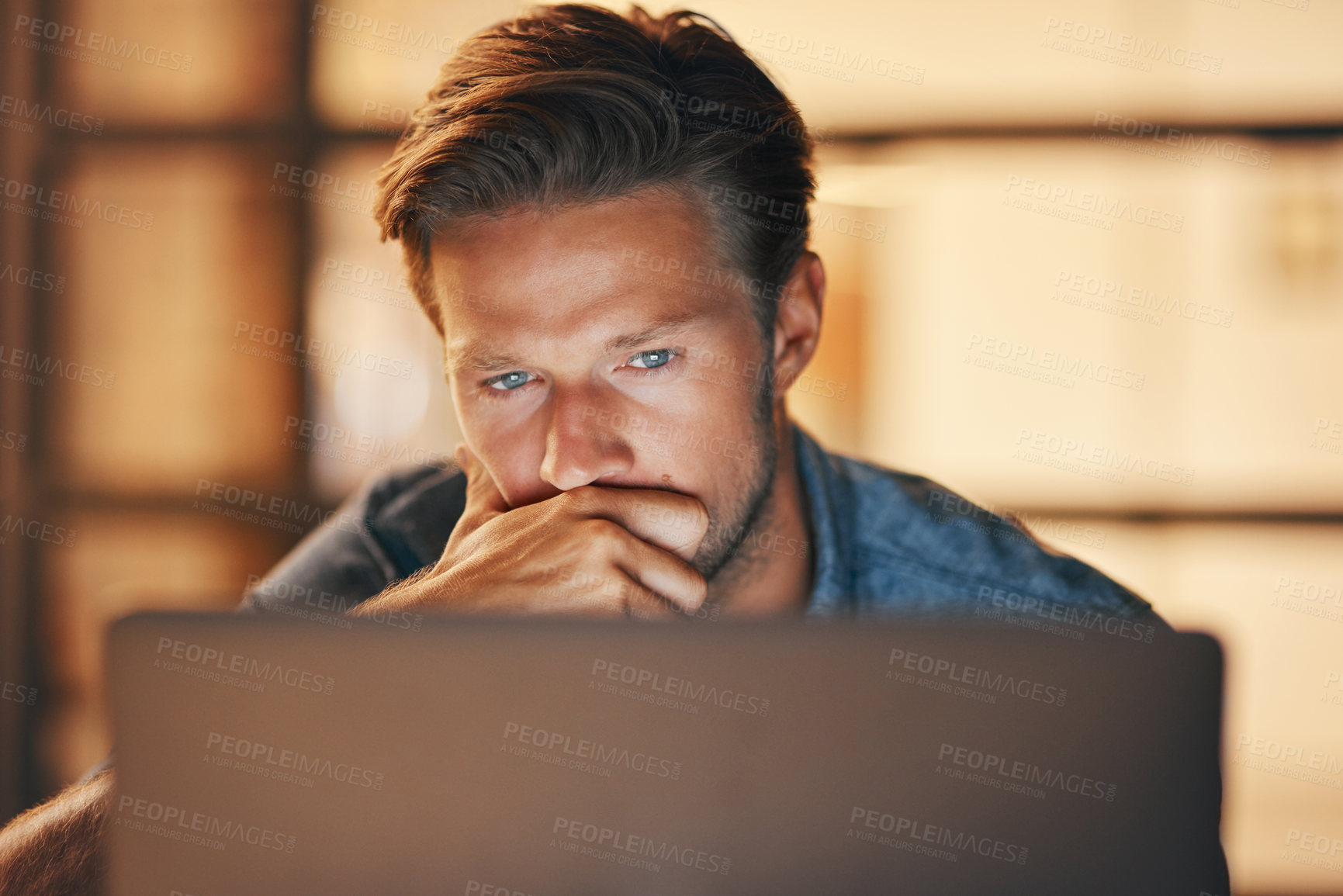 Buy stock photo Shot of a handsome young man looking thoughtful while working late in his office