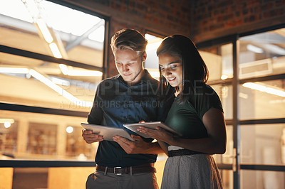 Buy stock photo Shot of two designers using their digital tablets while working nightshift