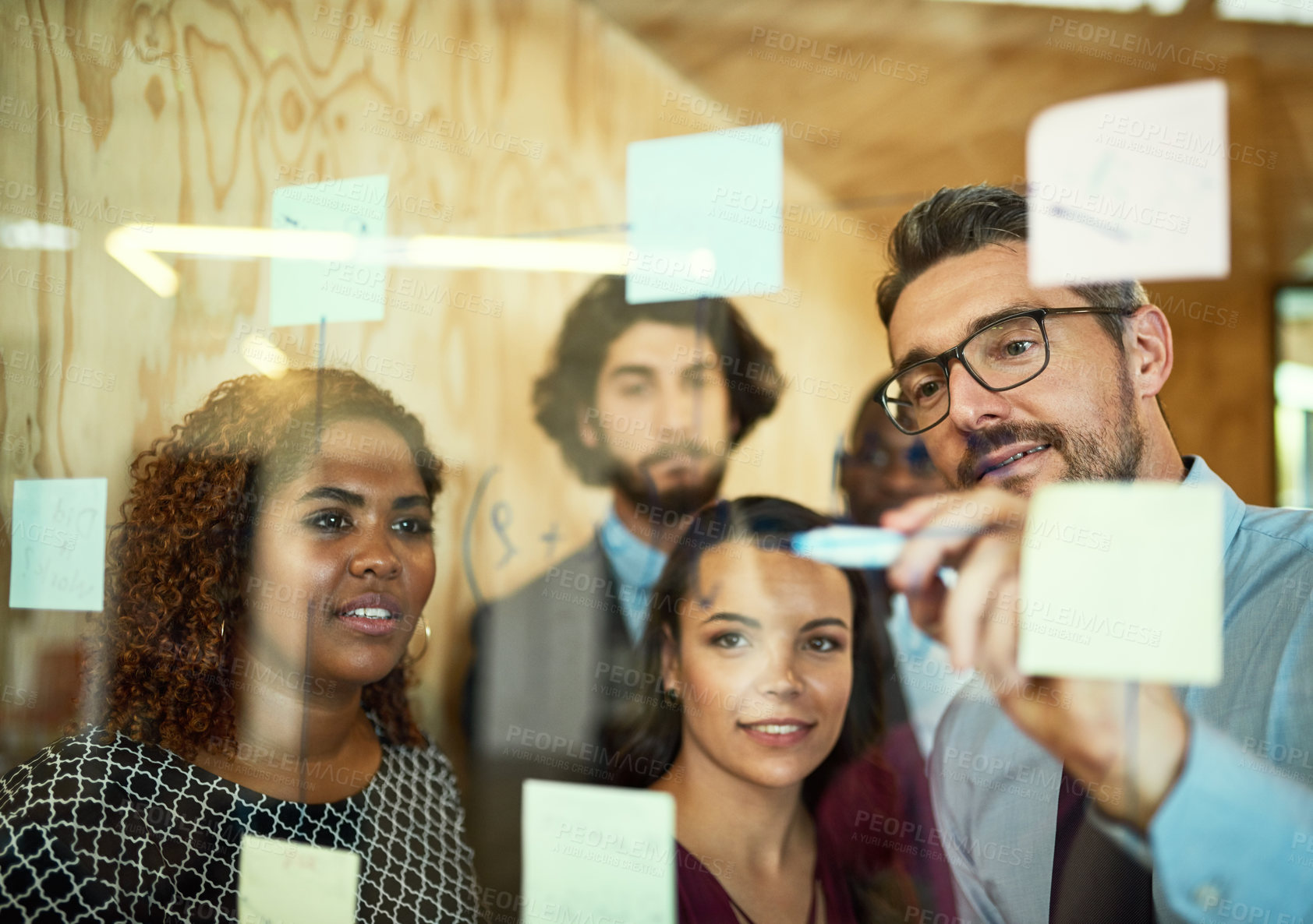 Buy stock photo Cropped shot of coworkers using sticky notes on a glass wall during a meeting in the office