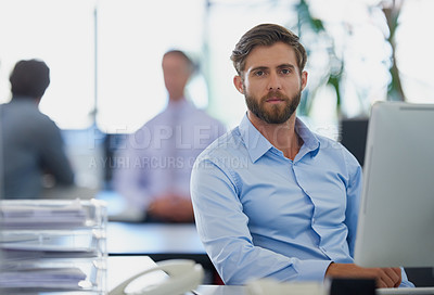 Buy stock photo Portrait of a handsome young businessman sitting in an office with his colleagues in the background