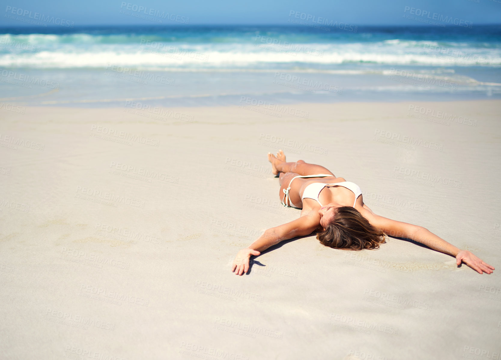 Buy stock photo Shot of a sexy young woman lying on the beach in a bikini
