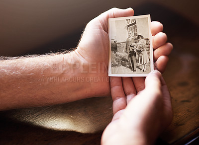 Buy stock photo Cropped shot a man holding an old black and white photograph of himself and his wife