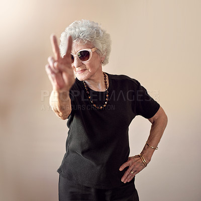 Buy stock photo Shot of a cool senior woman wearing sunglasses and showing a peace gesture