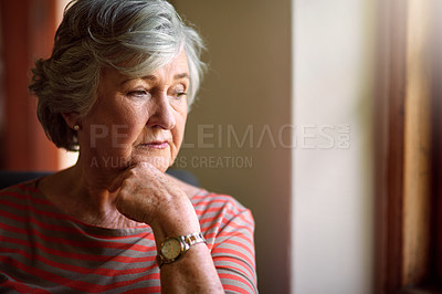 Buy stock photo Shot of a thoughtful senior woman looking out of the window at home