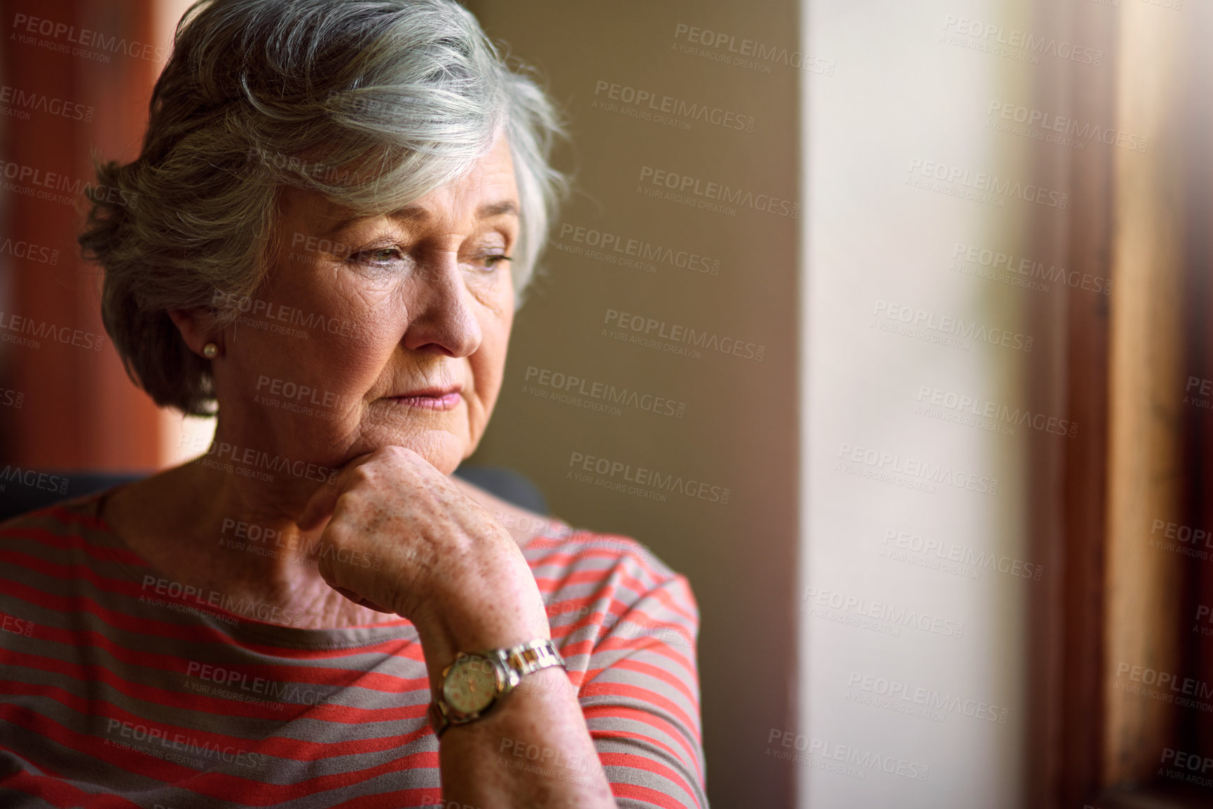 Buy stock photo Shot of a thoughtful senior woman looking out of the window at home