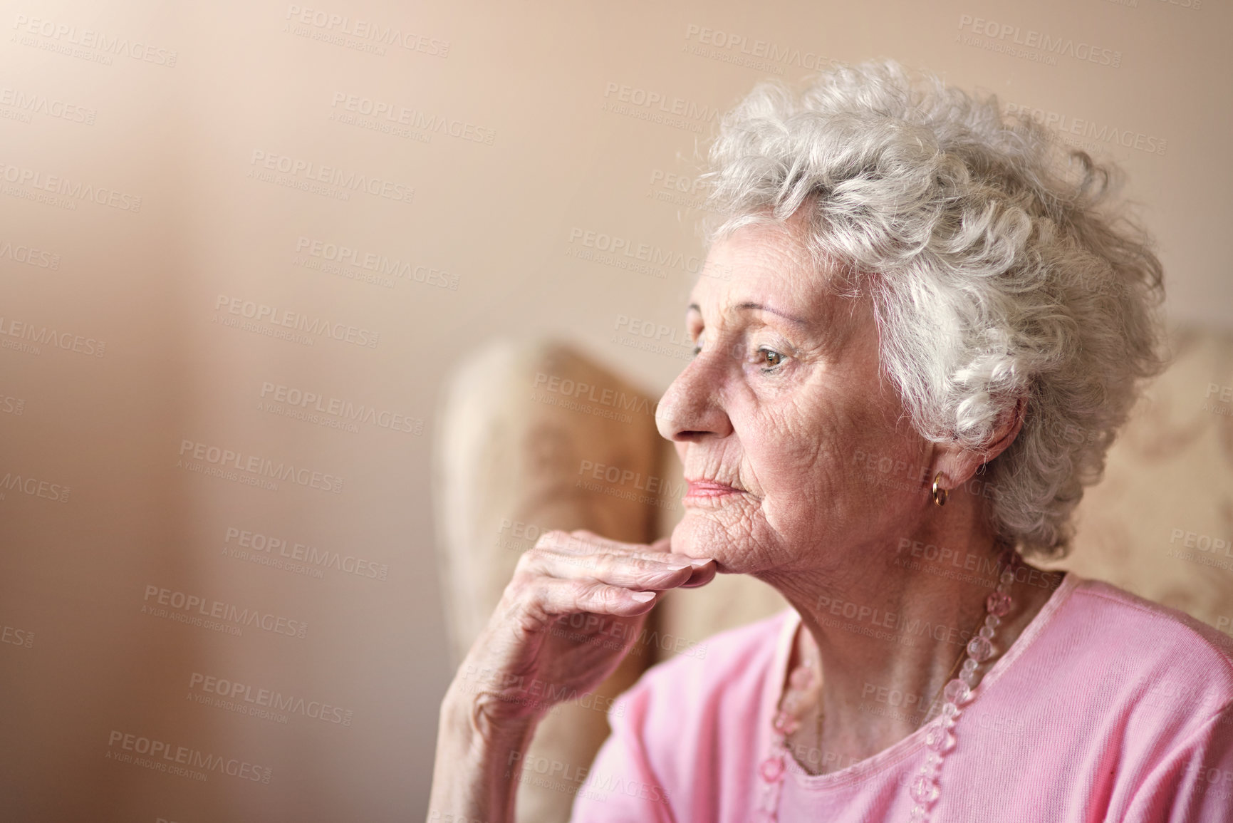Buy stock photo Shot of a senior woman sitting on a chair and looking thoughtful at home