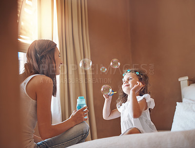 Buy stock photo Mom, girl and blowing bubbles in house for bonding, development and relationship together on bed. Woman, child and playing games in apartment with soap, water and toys for childhood fun activity