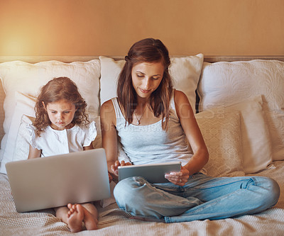 Buy stock photo Shot of a little girl using a laptop and her mother using a digital tablet at home