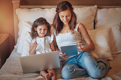 Buy stock photo Shot of a little girl using a laptop and her mother using a digital tablet at home