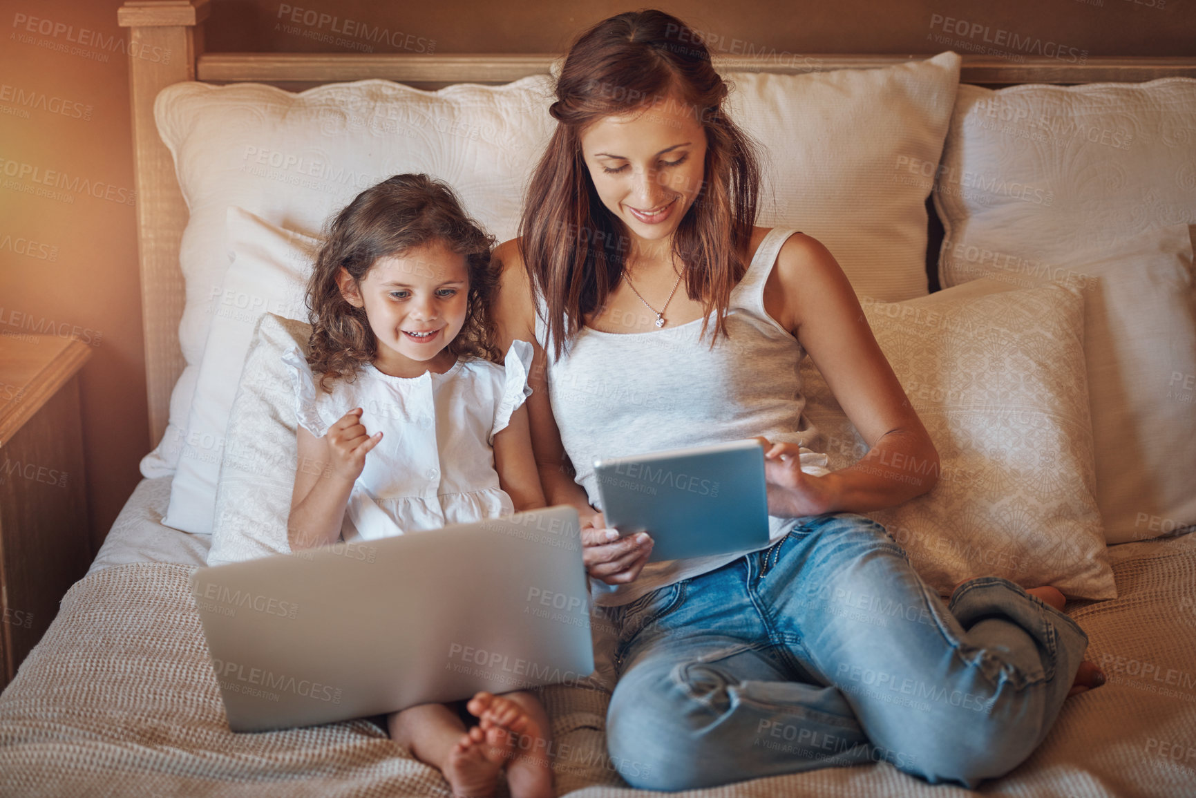 Buy stock photo Shot of a little girl using a laptop and her mother using a digital tablet at home