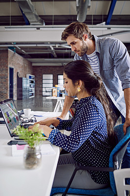 Buy stock photo Shot of two young designers working together on a laptop in an office