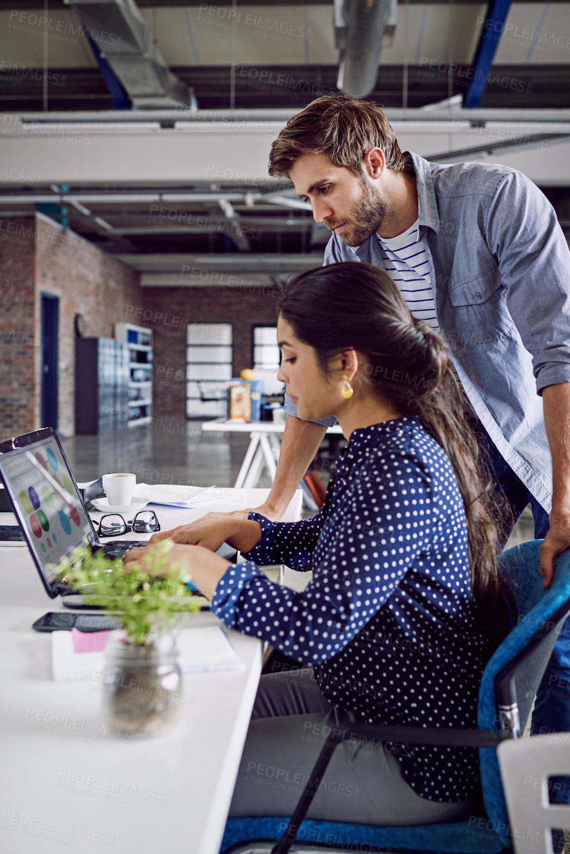 Buy stock photo Shot of two young designers working together on a laptop in an office