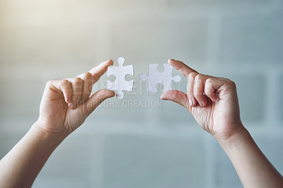 Buy stock photo Hands, puzzle and synergy with a business woman in the office against a brick wall for building or connection. Idea, innovation and strategy with a female employee holding jigsaw pieces at work