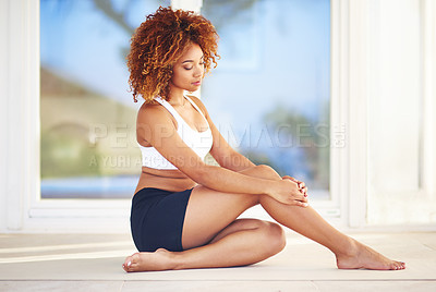Buy stock photo Shot of a sporty young woman looking thoughtful while sitting on the floor