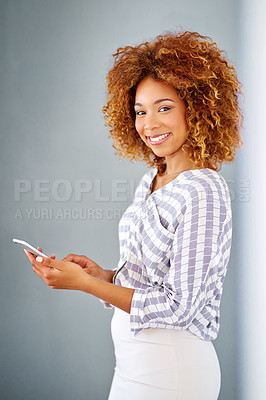 Buy stock photo Studio shot of a young woman using her cellphone against a grey background