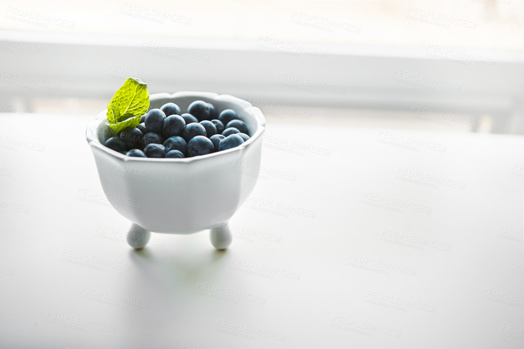 Buy stock photo Shot of fresh blueberries in a bowl on a white table