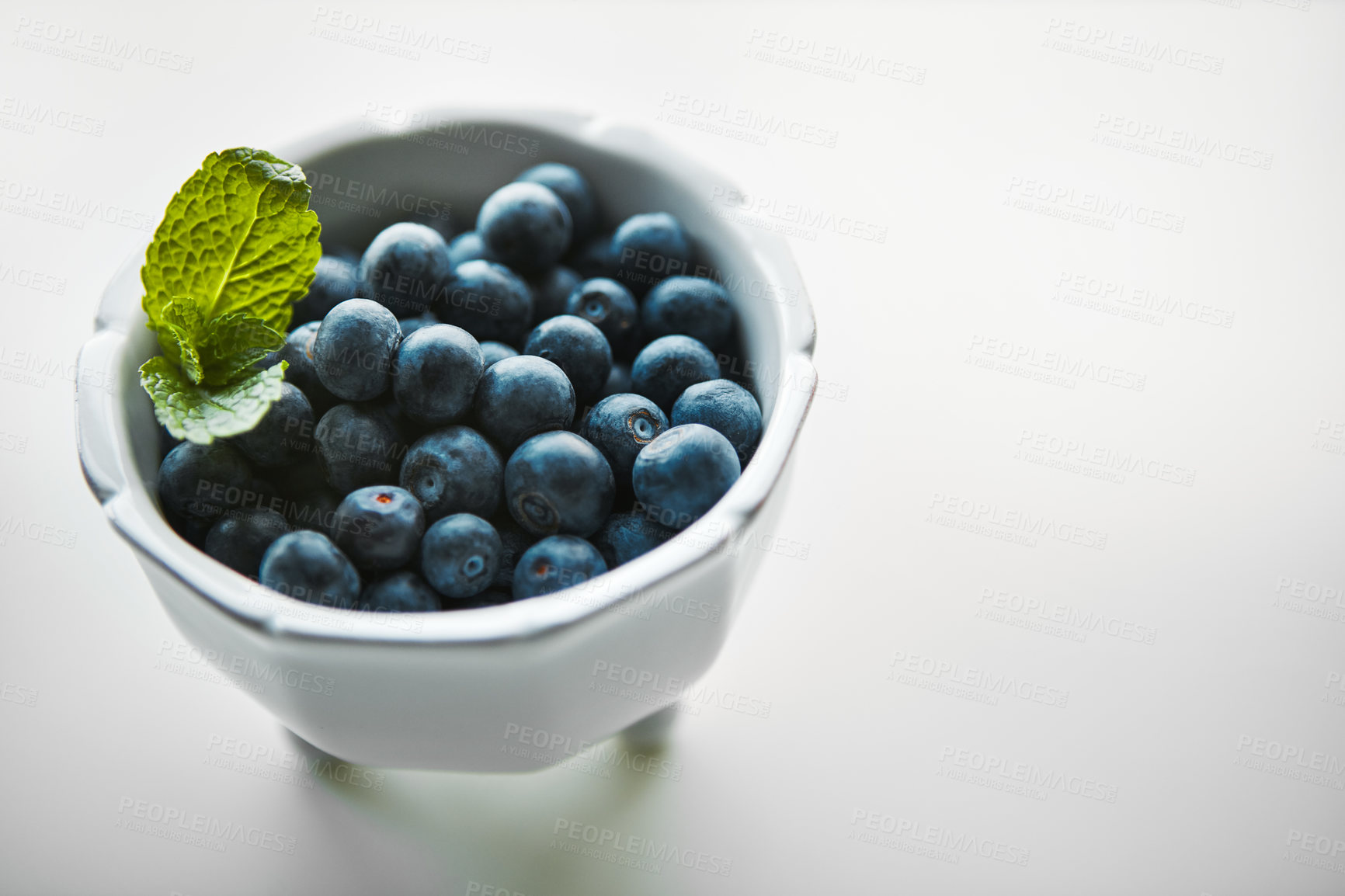 Buy stock photo Shot of fresh blueberries in a bowl on a white table