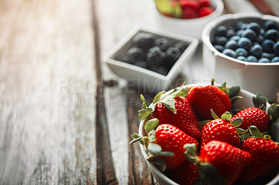 Buy stock photo Bowls, berries and table in kitchen for wellness with organic choice for nutrition, breakfast or closeup in home. Fruits, strawberry and raspberry with container, meal prep or healthy diet in morning