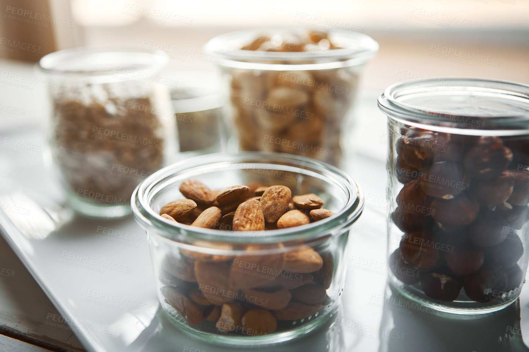 Buy stock photo Bowls, nuts and seeds on plate, kitchen and hazelnut for nutrition, health and table with diet for wellness. Cashew, almond and storage in glass container for meal prep with food in morning at house