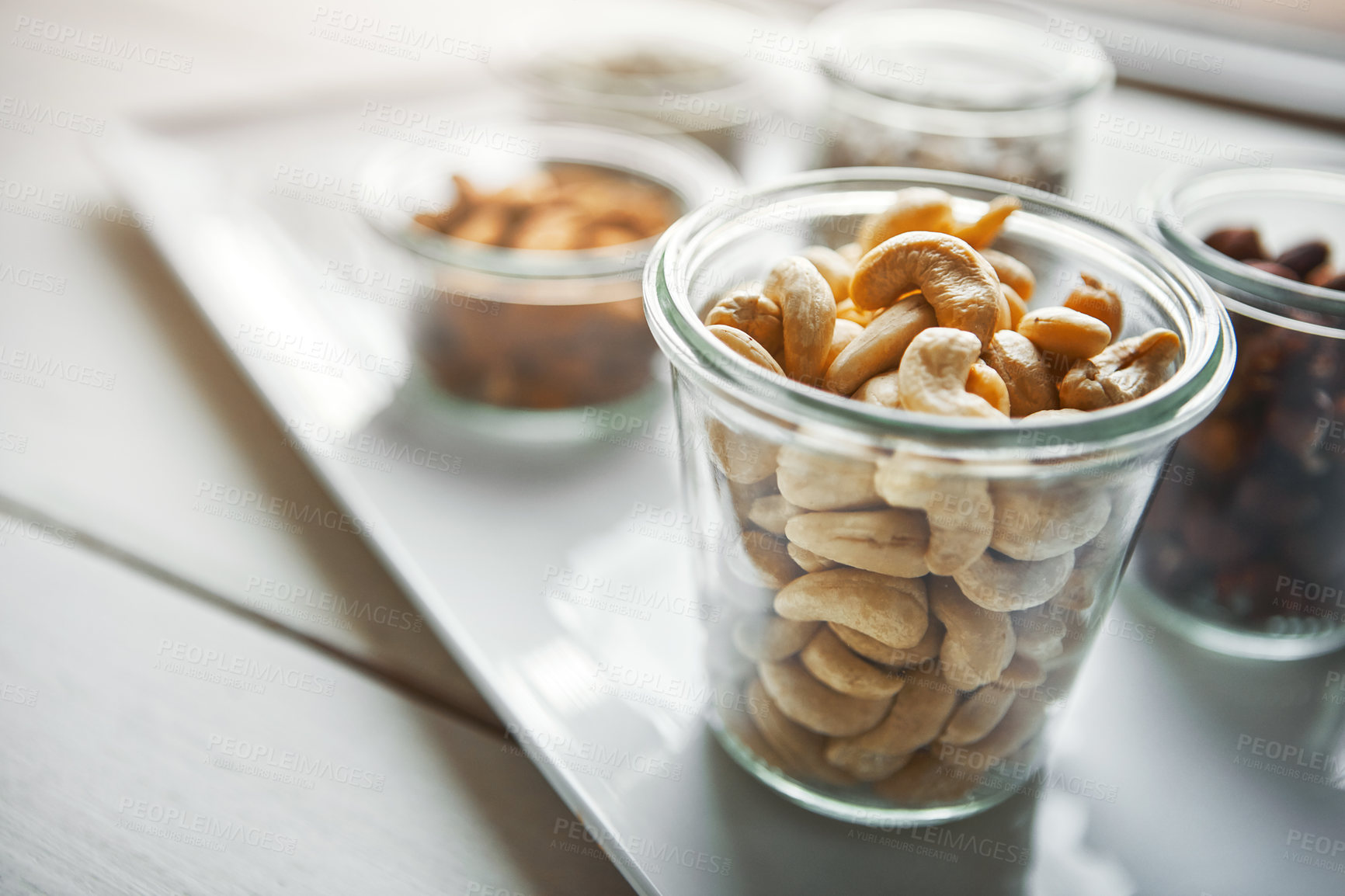 Buy stock photo Bowls, nuts and cashew on plate, kitchen or breakfast for nutrition, health or table with diet for wellness. Hazelnut, almond and storage in glass container for meal prep, food and morning at house