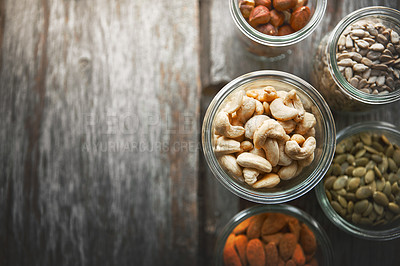 Buy stock photo Bowls, cashew and nuts on table, above and mock up space for nutrition, health and promotion for wellness. Almond, hazelnut and pumpkin seeds in glass container for meal prep with food at apartment