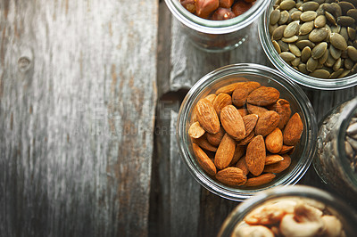 Buy stock photo Bowls, almond and nuts on table, above and mock up space for nutrition, health and promotion for wellness. Cashew, hazelnut and pumpkin seeds in glass container for meal prep with food at apartment