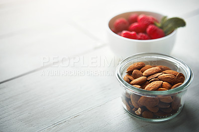 Buy stock photo Shot of fresh nuts in a bowl with raspberries blurred in the background