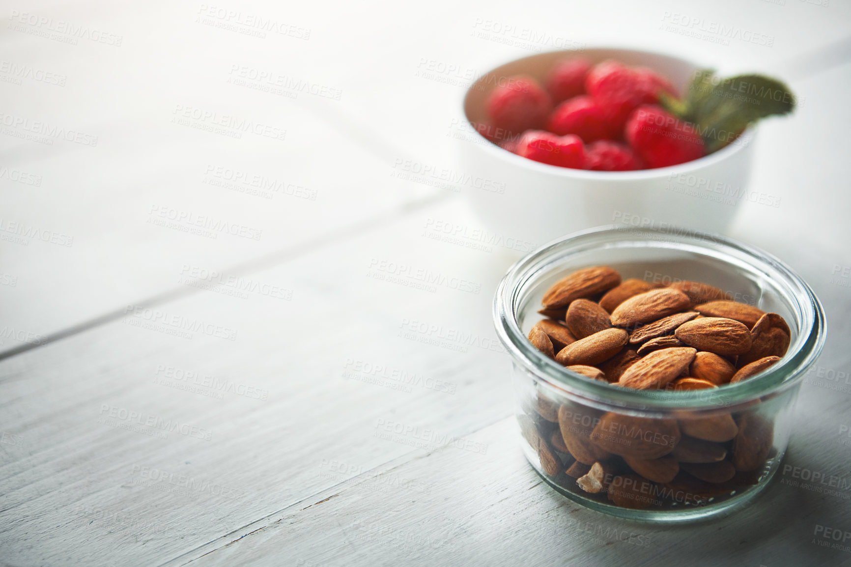 Buy stock photo Shot of fresh nuts in a bowl with raspberries blurred in the background